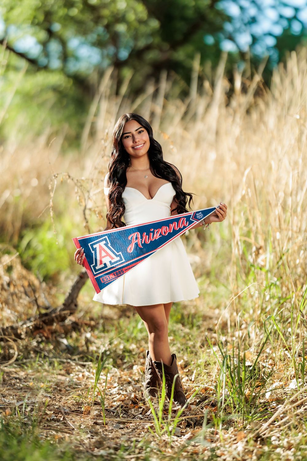 Tucson, AZ senior girl in grass with big trees holding a UofA pennant