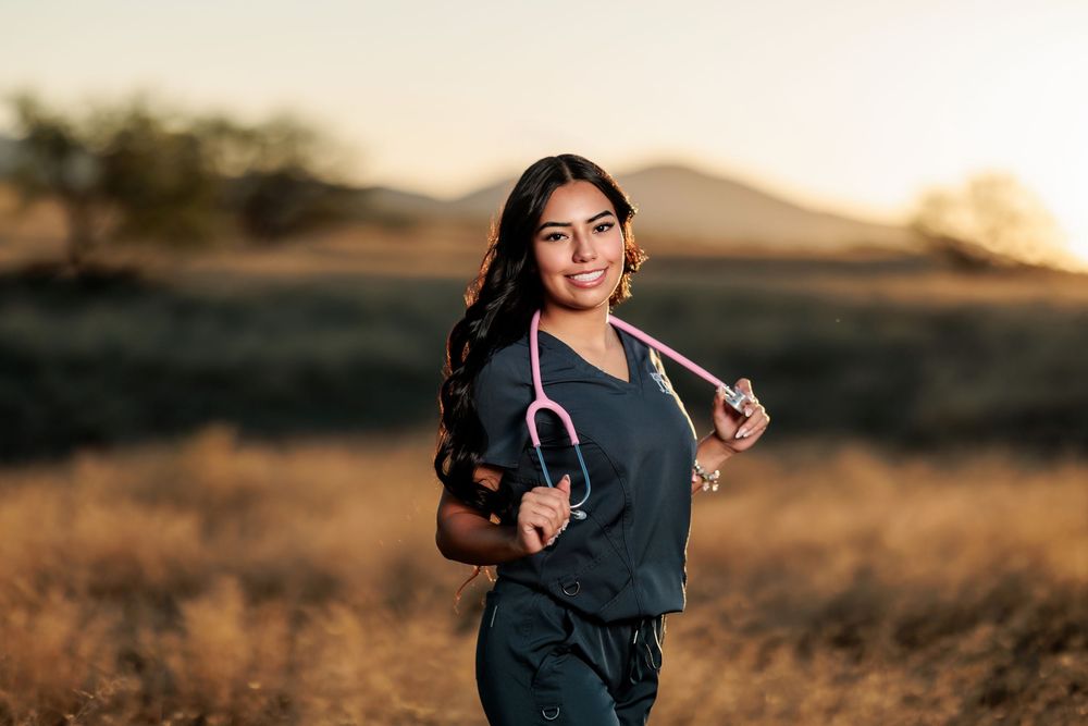 Tucson, AZ senior girl in a field at golden hour with scrubs a a stethoscope