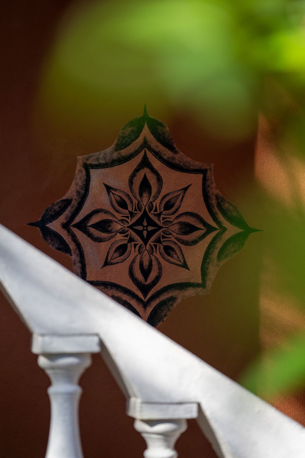 Decorative wooden star pattern detail on white railing with soft focus background.