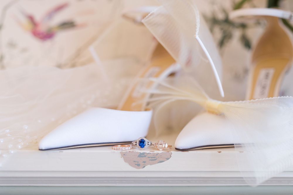 Wedding ring and elegant jewelry on an open book with soft white feathers.