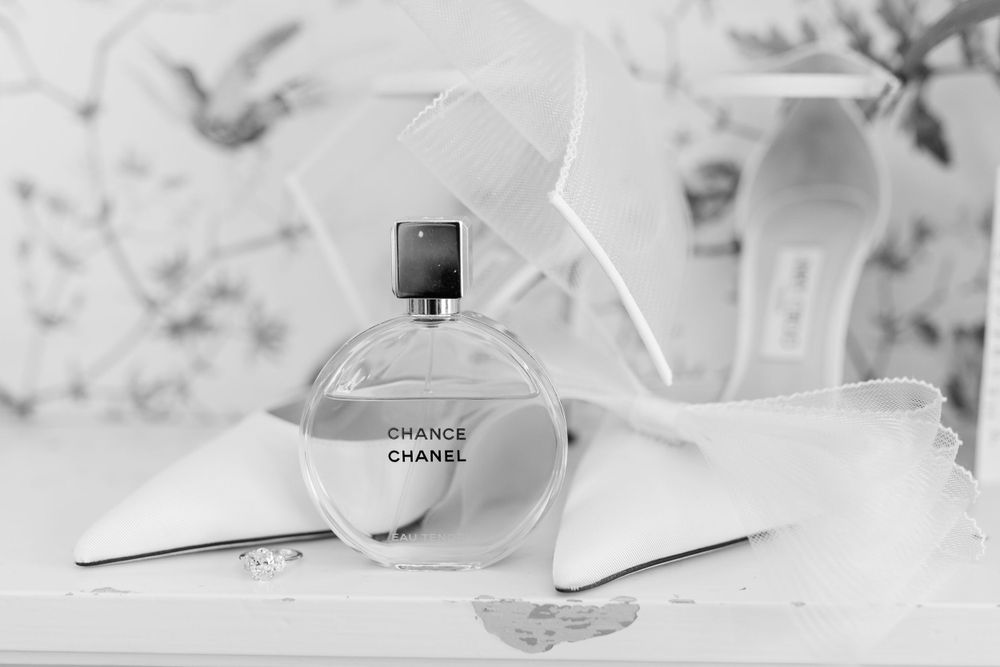 Black and white photograph of a Chanel perfume bottle with white feathers.