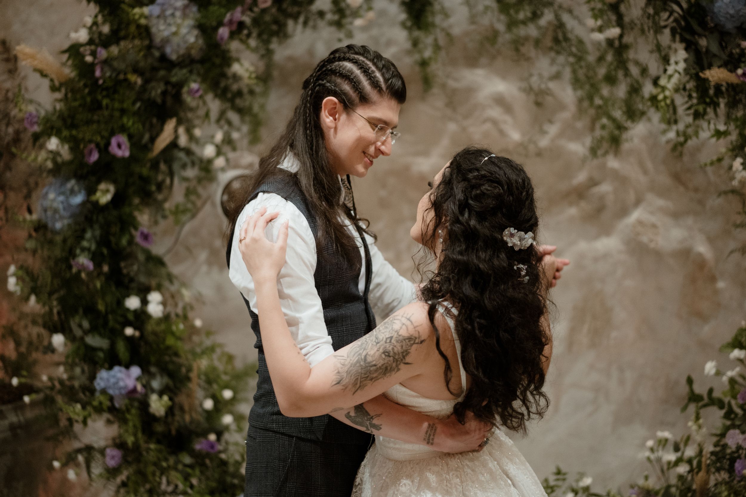 Intimate moment between newlyweds against a floral backdrop.