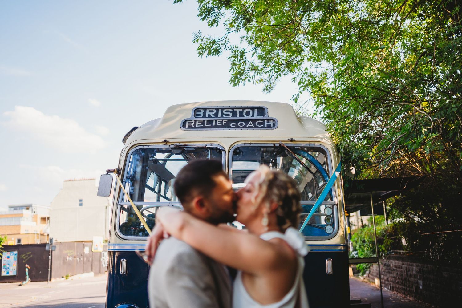 Vintage Bristol bus parked outdoors with trees in background during couples wedding photos in Bristol