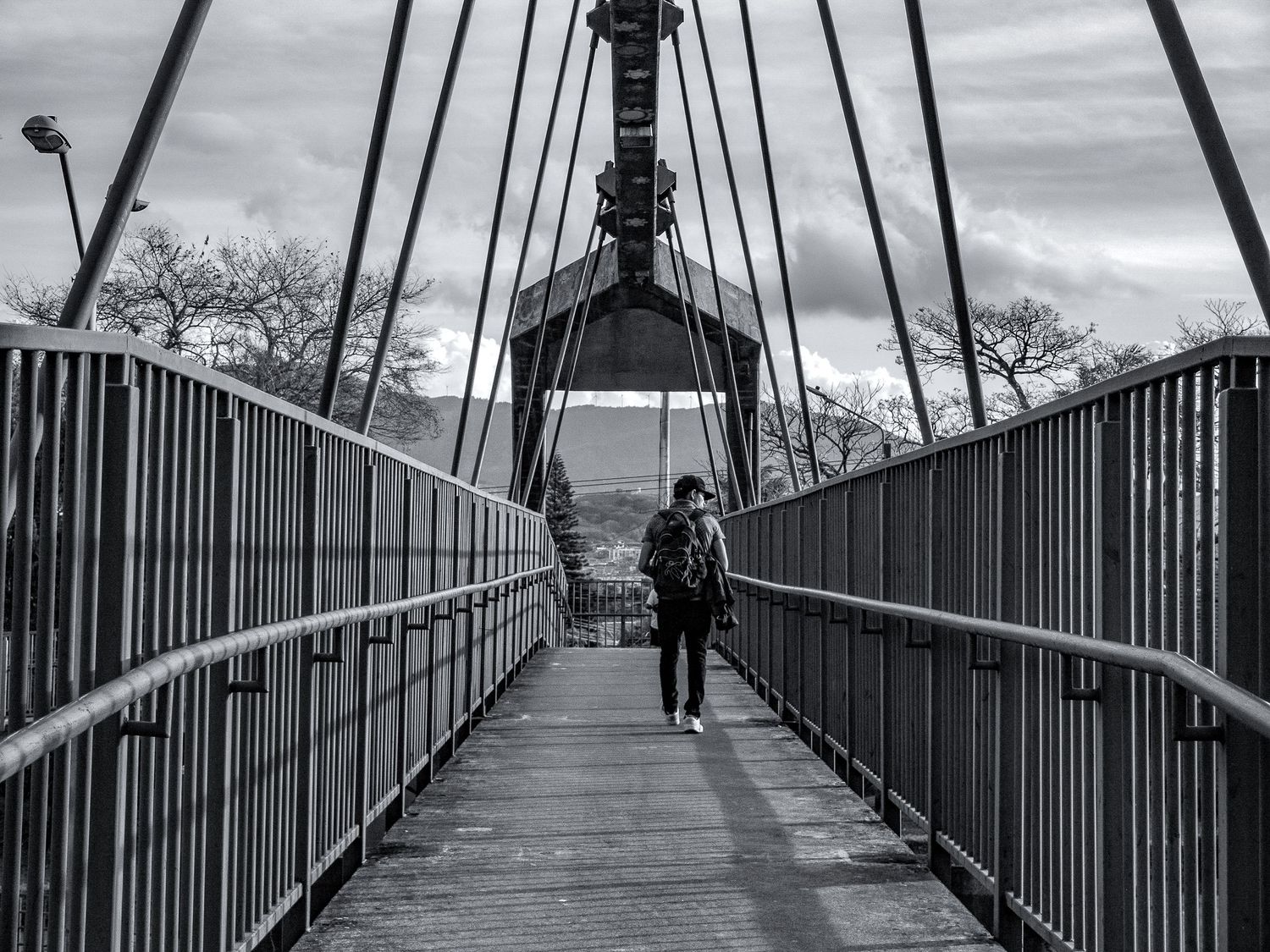 Black and white photograph of a symmetrical pedestrian bridge with metal railings.