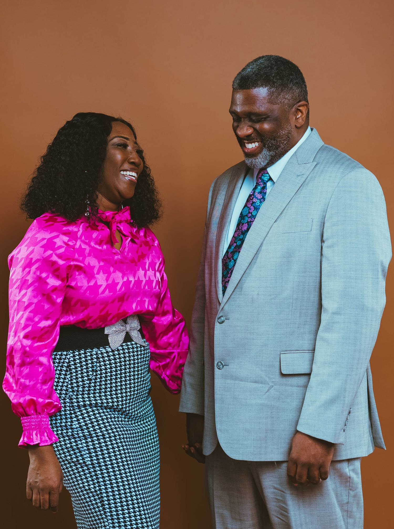 A couple laughing together wearing coordinated formal outfits.