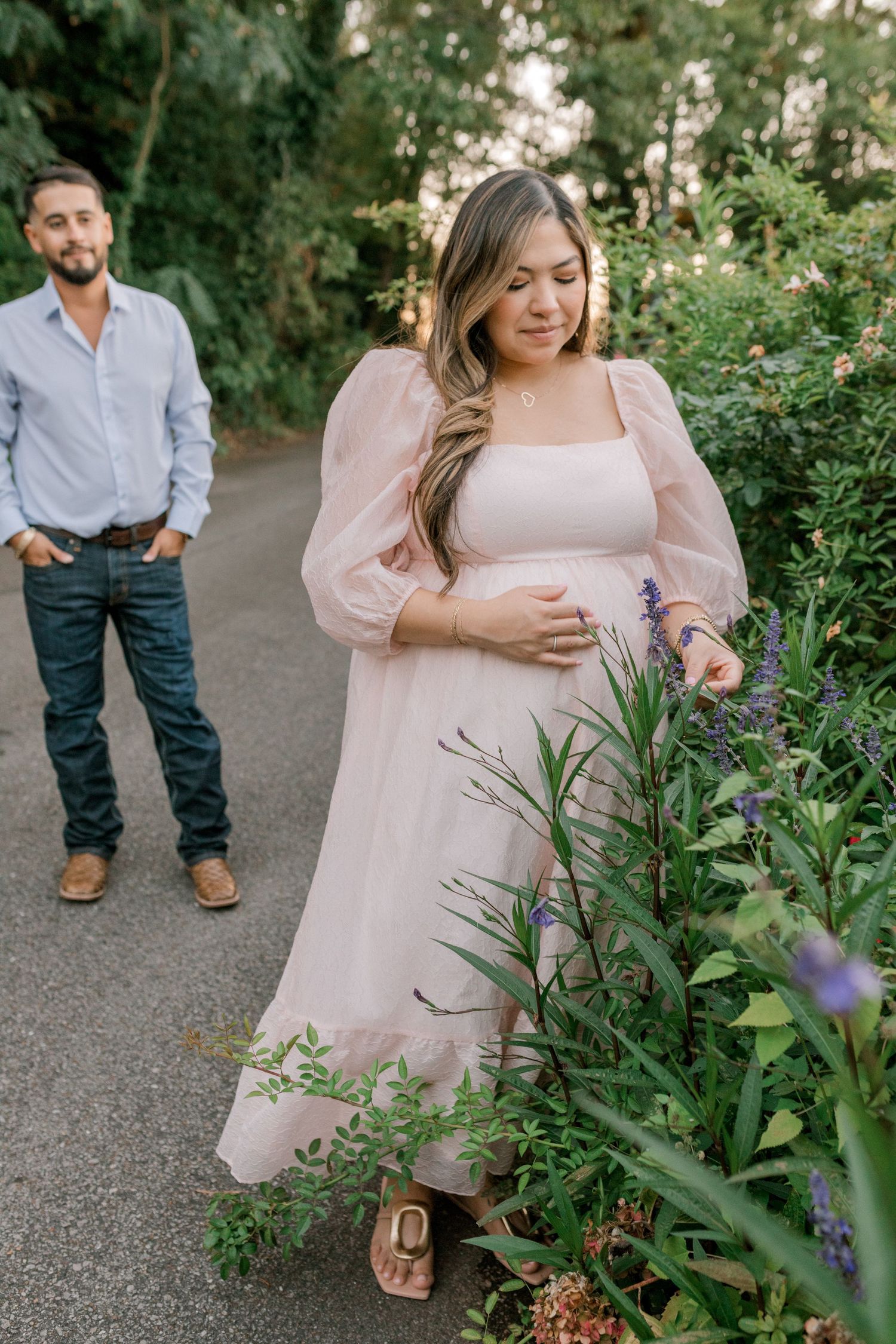 Expecting couple poses in garden path during maternity photoshoot.