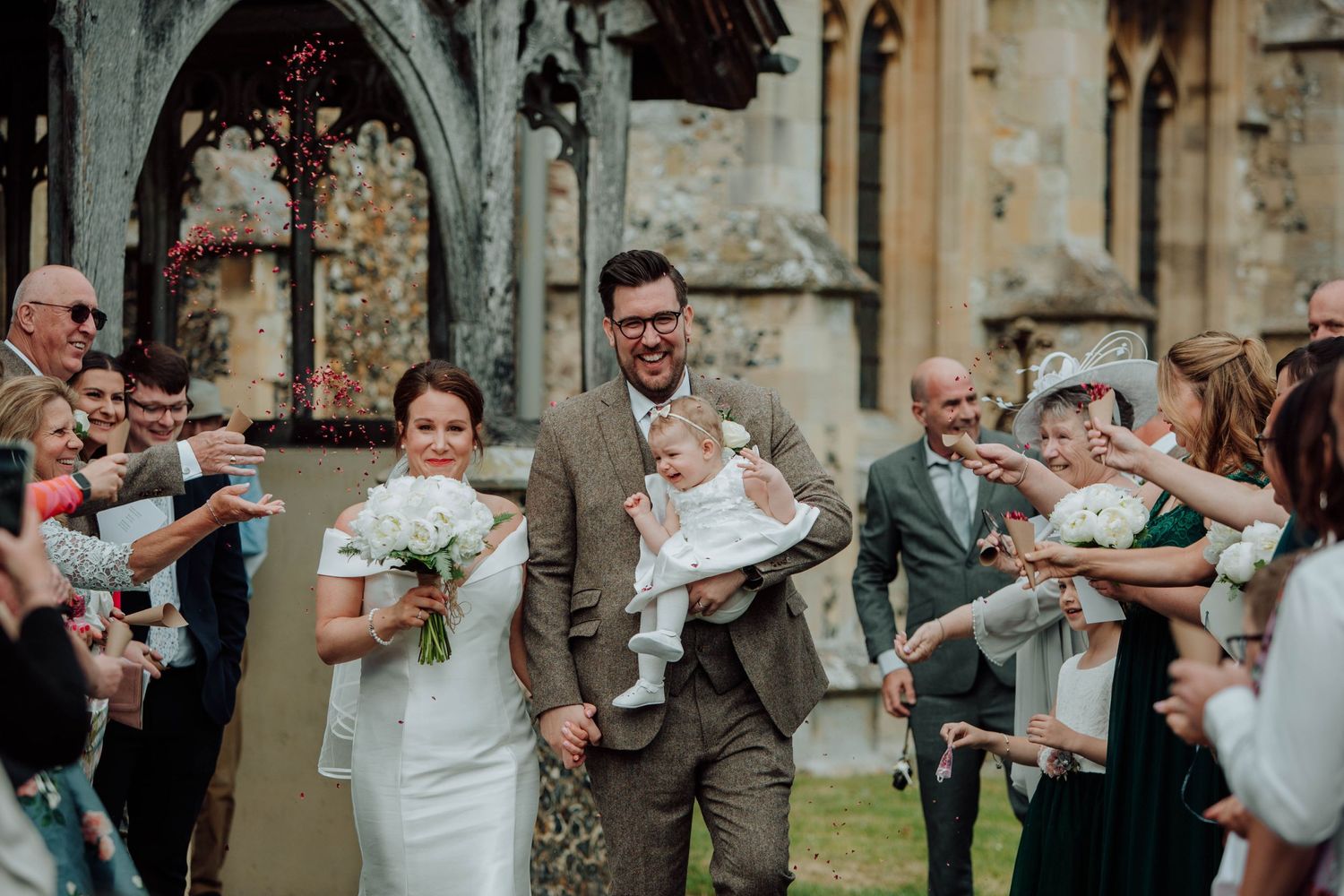 Wedding guests shower the newlyweds with confetti outside a historic church.