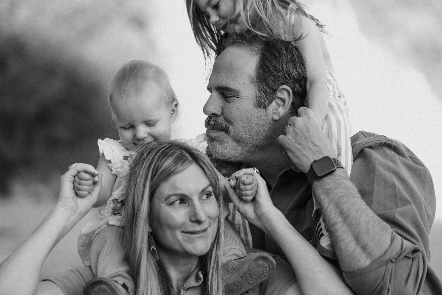 Black and white family portrait of parents with a baby, creating a joyful and tender moment together.