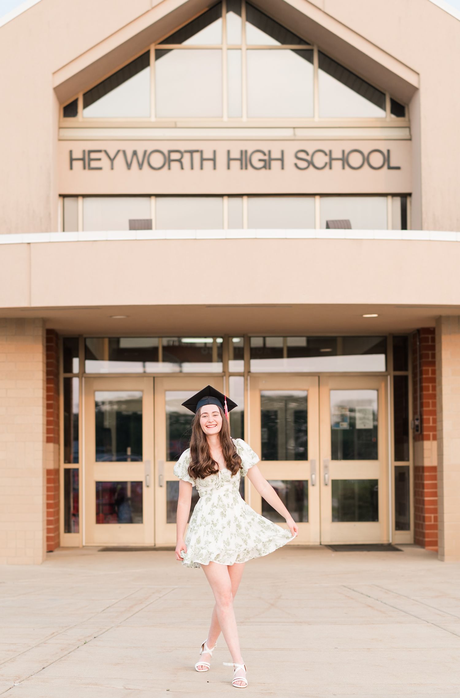 Heyworth, Illinois high school senior swinging her dress and laughing during a cap and gown session by Julie Loy Photography