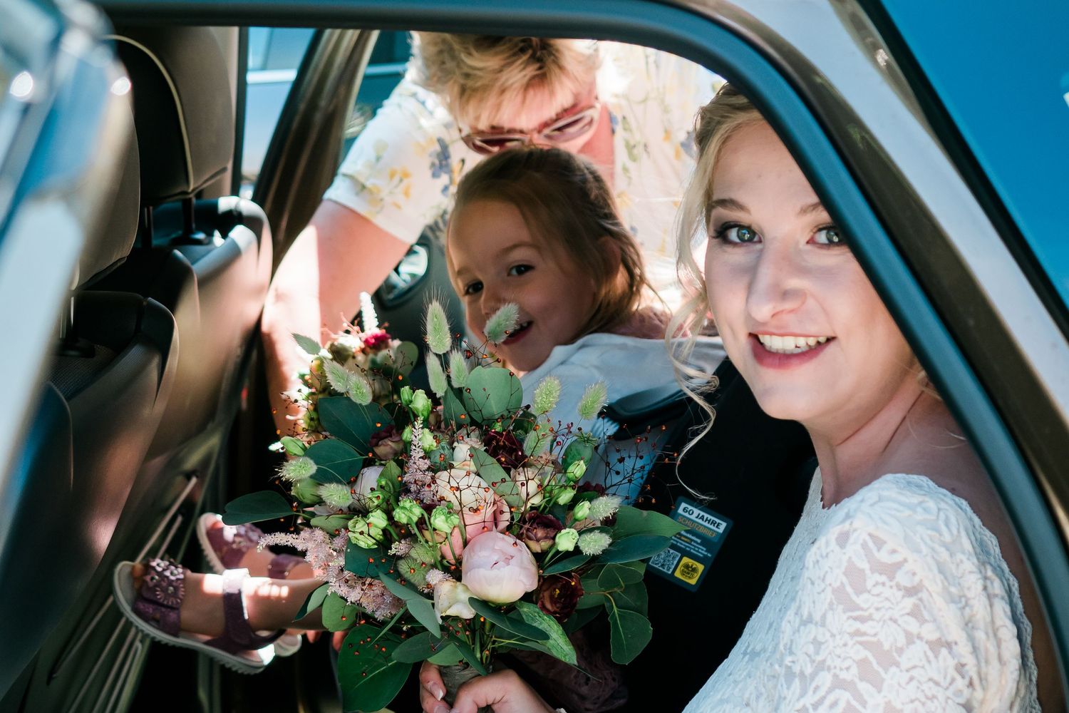 Bride with bouquet of flowers inside a blue car in Switzerland