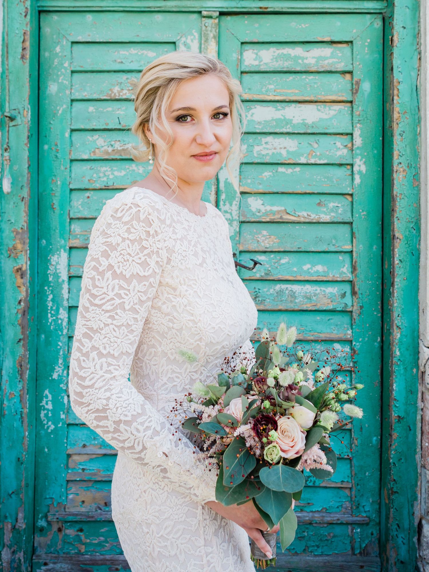 Beautiful bride looking at camera with yvory dress and holding flowers
