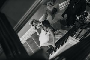 High angle view of a bride descending an elegant staircase in a white dress.