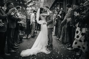 Black and white photo of newlyweds sharing their first dance surrounded by guests.