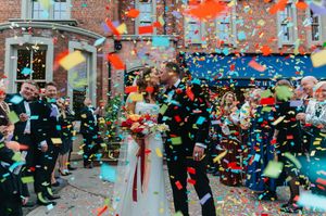 Colorful confetti rains down on a city street during a festive parade celebration with spectators watching from sidewalks.