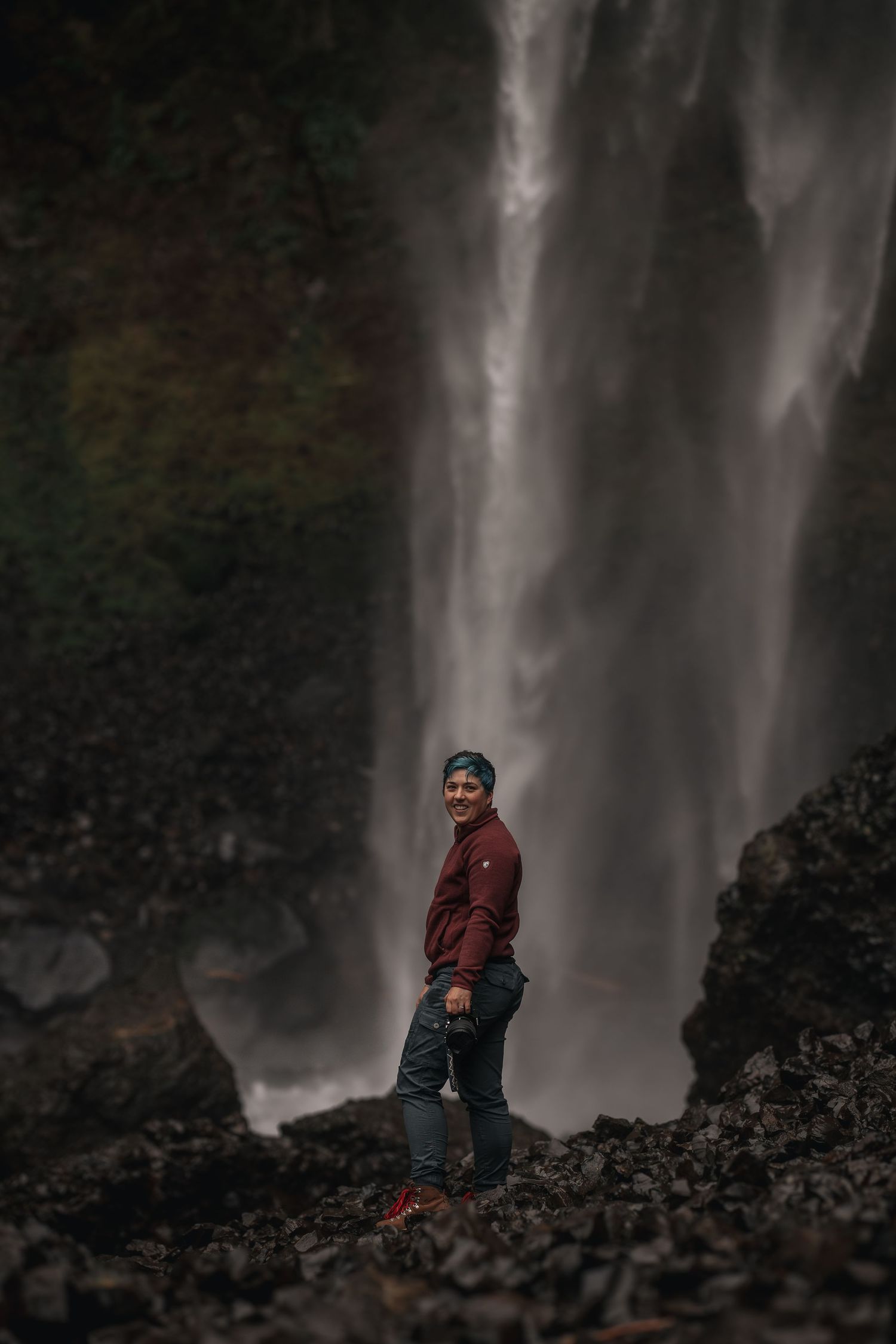 A young stands in front of Elowah falls in the Columbia river gorge on a moody Pacific Northwest day.