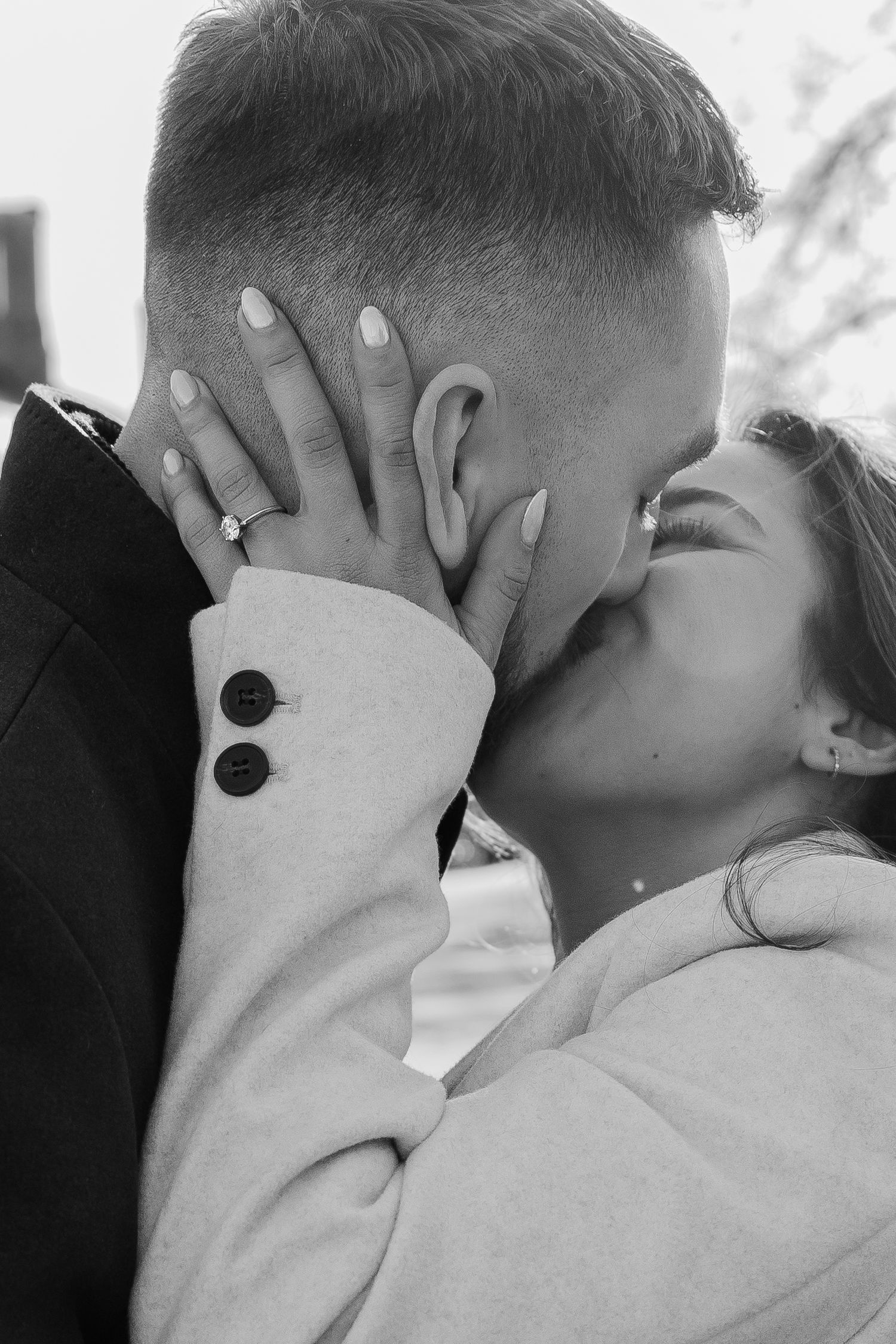 Black and white intimate portrait showing tender embrace and wedding rings.