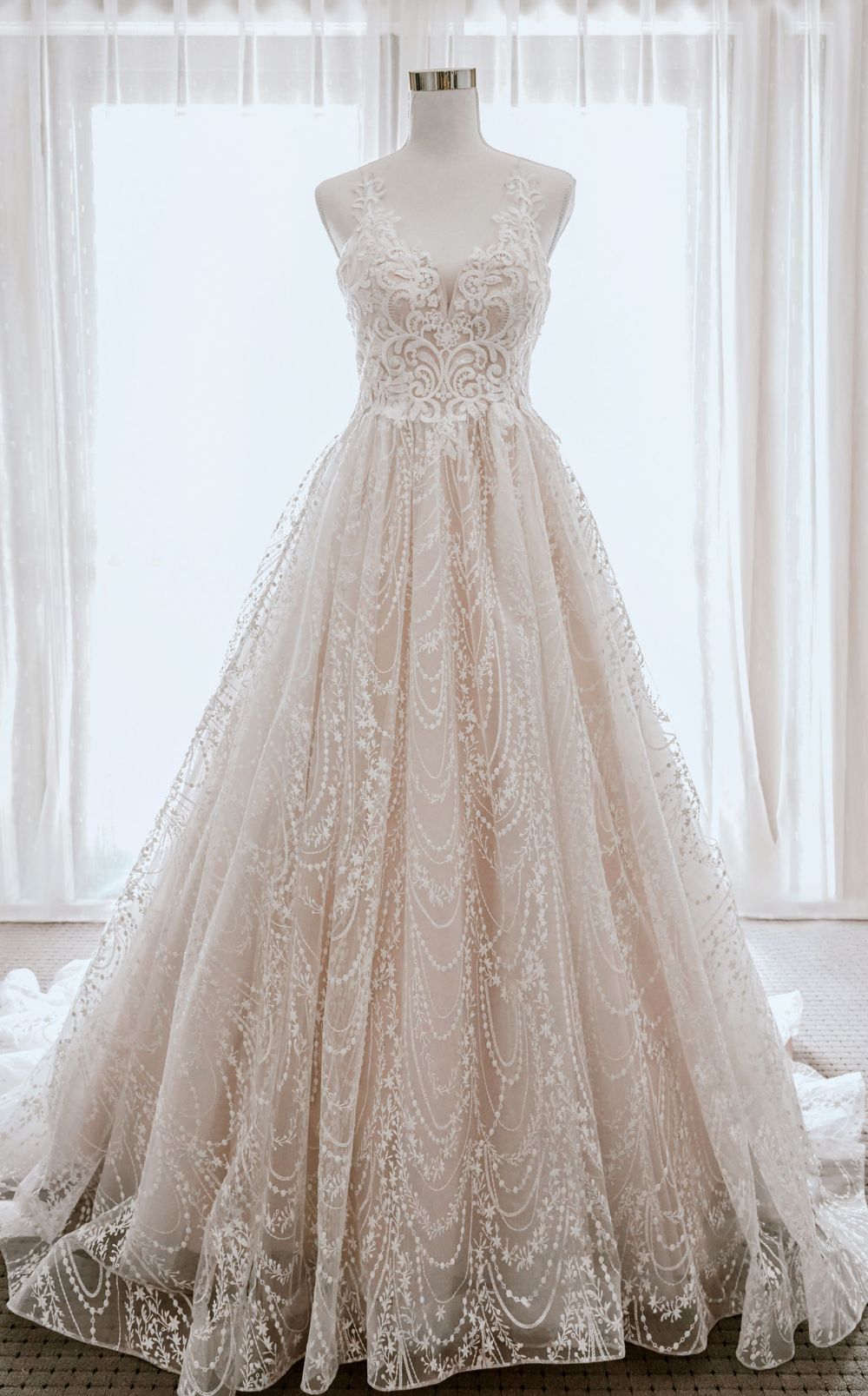 Stunning lace wedding dress with sweetheart neckline on mannequin against white backdrop.
