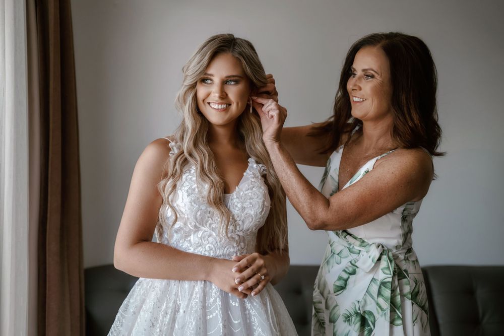 Two women share joyful moment while preparing for wedding celebration.