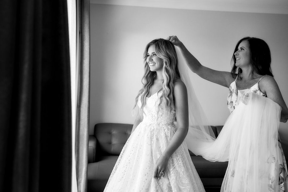 Black and white photo of bride getting hair styled on wedding day.