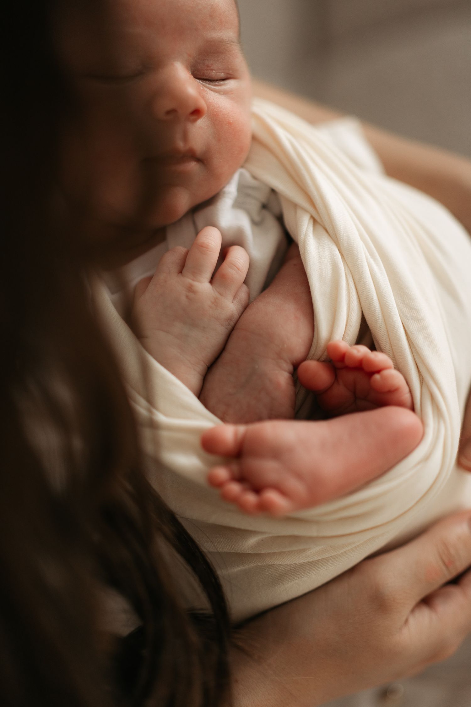 A peaceful black and white portrait of a sleeping newborn swaddled in soft fabric.