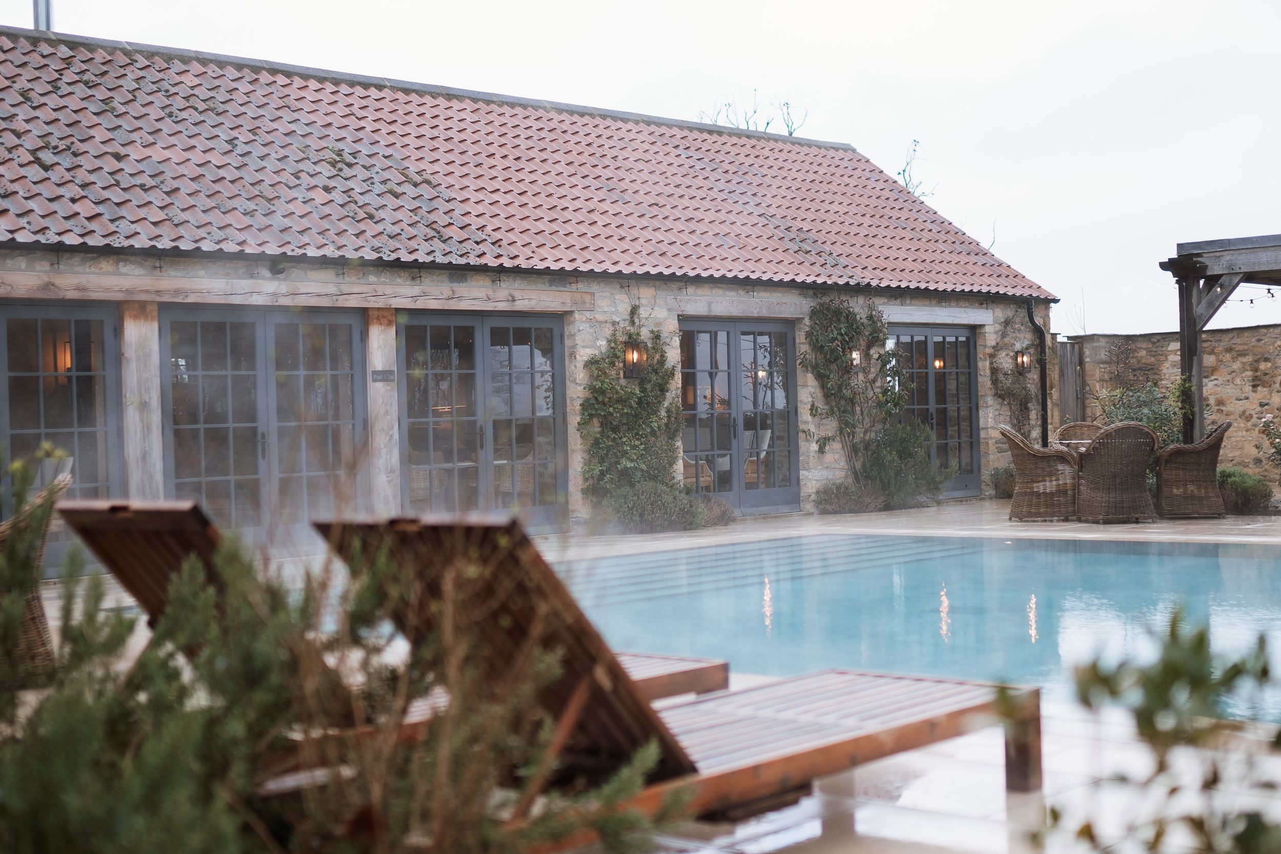 A luxury pool area with loungers and covered patio at a rustic countryside retreat at Middleton lodge