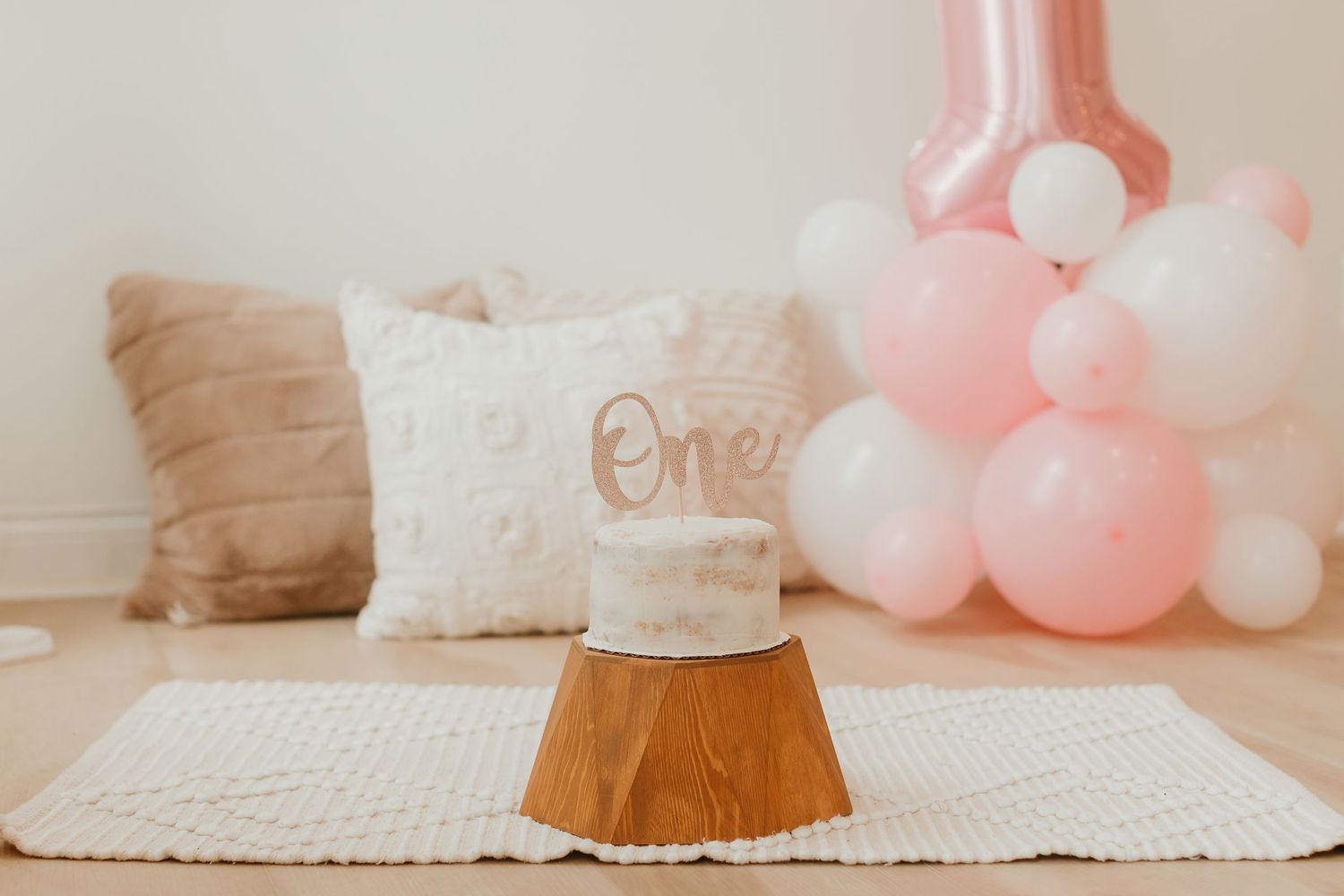 Pink balloon display and white decorations for first birthday celebration.