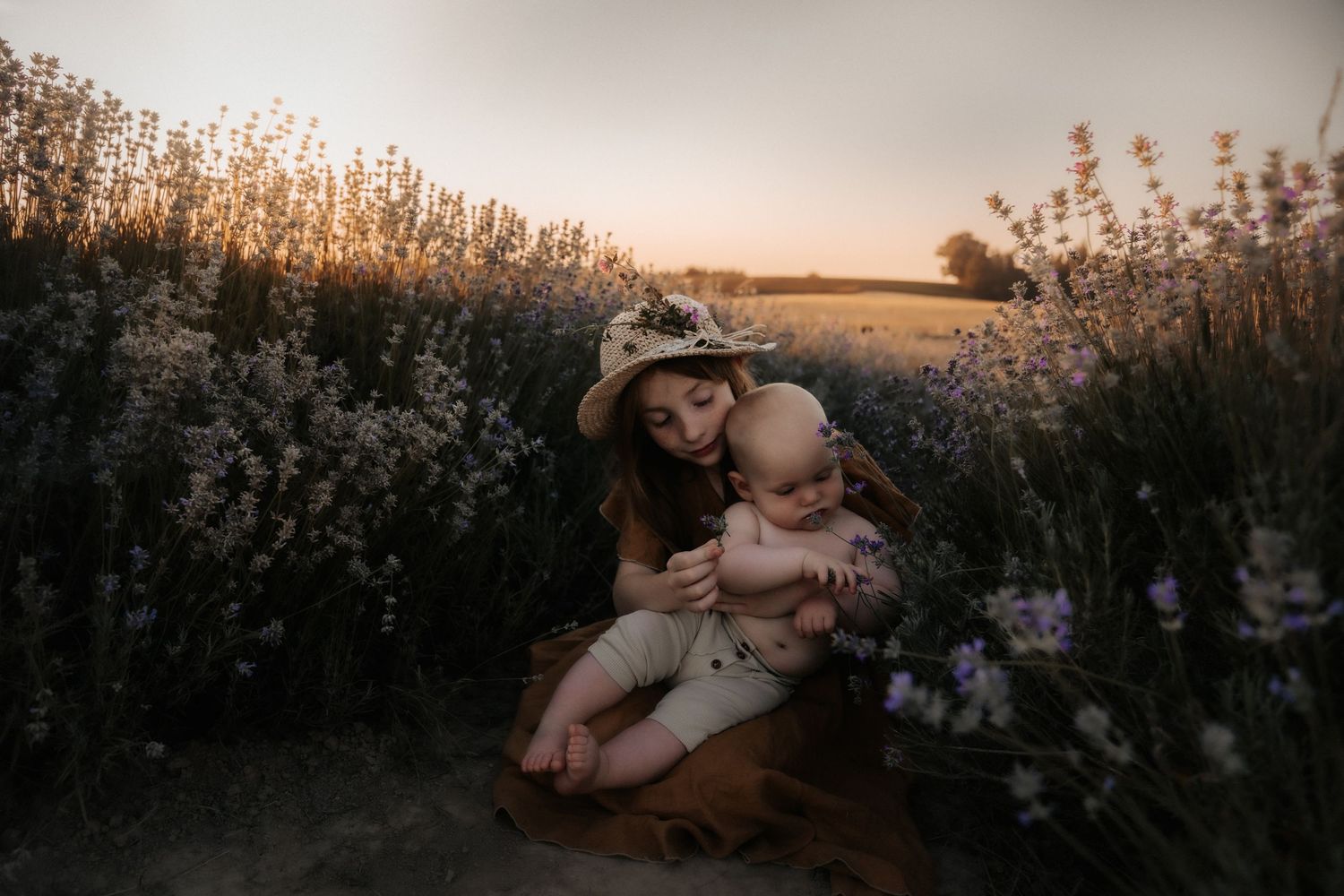 A family shares an intimate moment together in a mountain field at dusk.