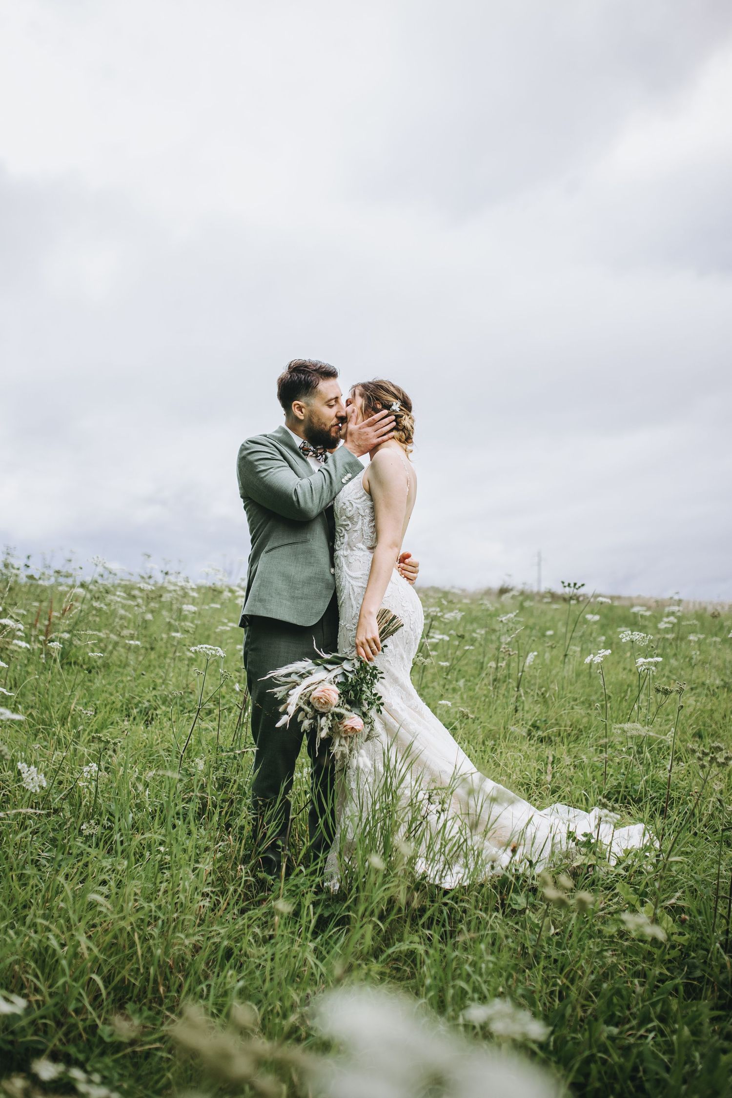A couple walks through a meadow of wildflowers during their wedding photoshoot.