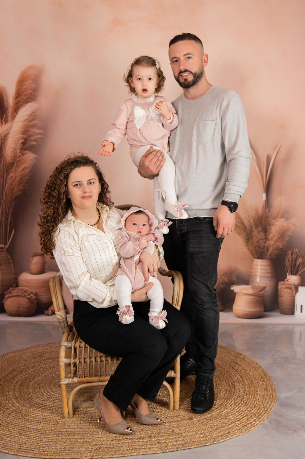Studio family portrait with rustic decor and woven chair on circular jute rug.