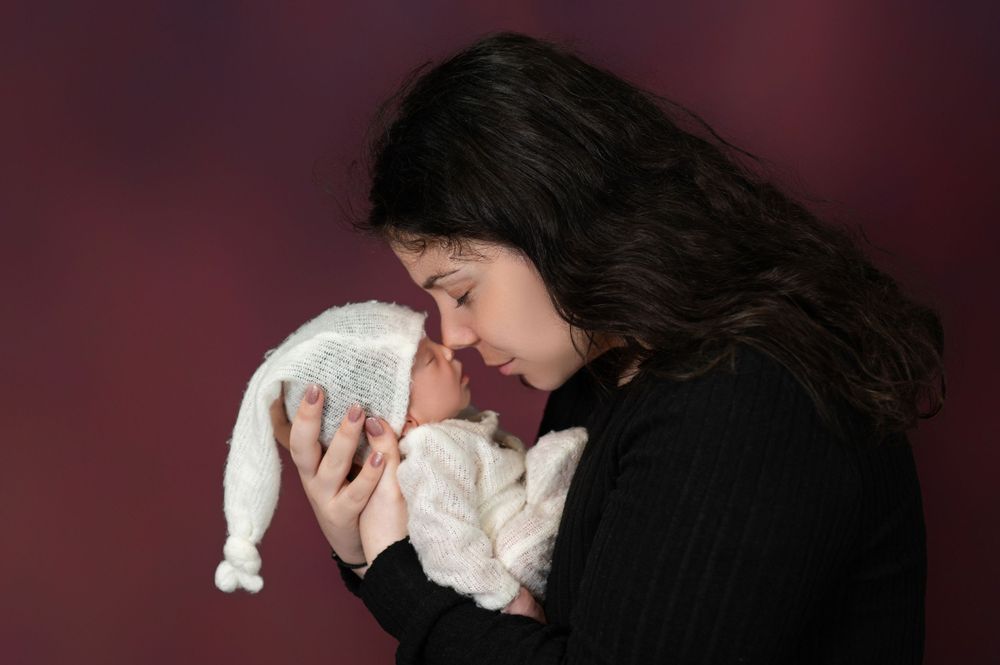 A series of black and white artistic newborn baby photos showing gentle cradling and holding positions.