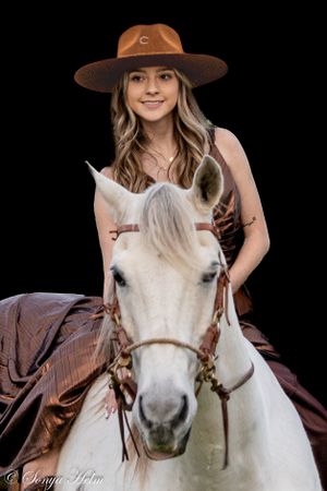 Dramatic portrait against black background showcasing white horse with western riding gear.