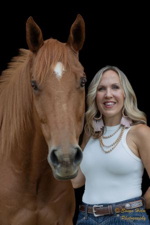 A close-up portrait of a chestnut horse with white blaze and companion against dark background.