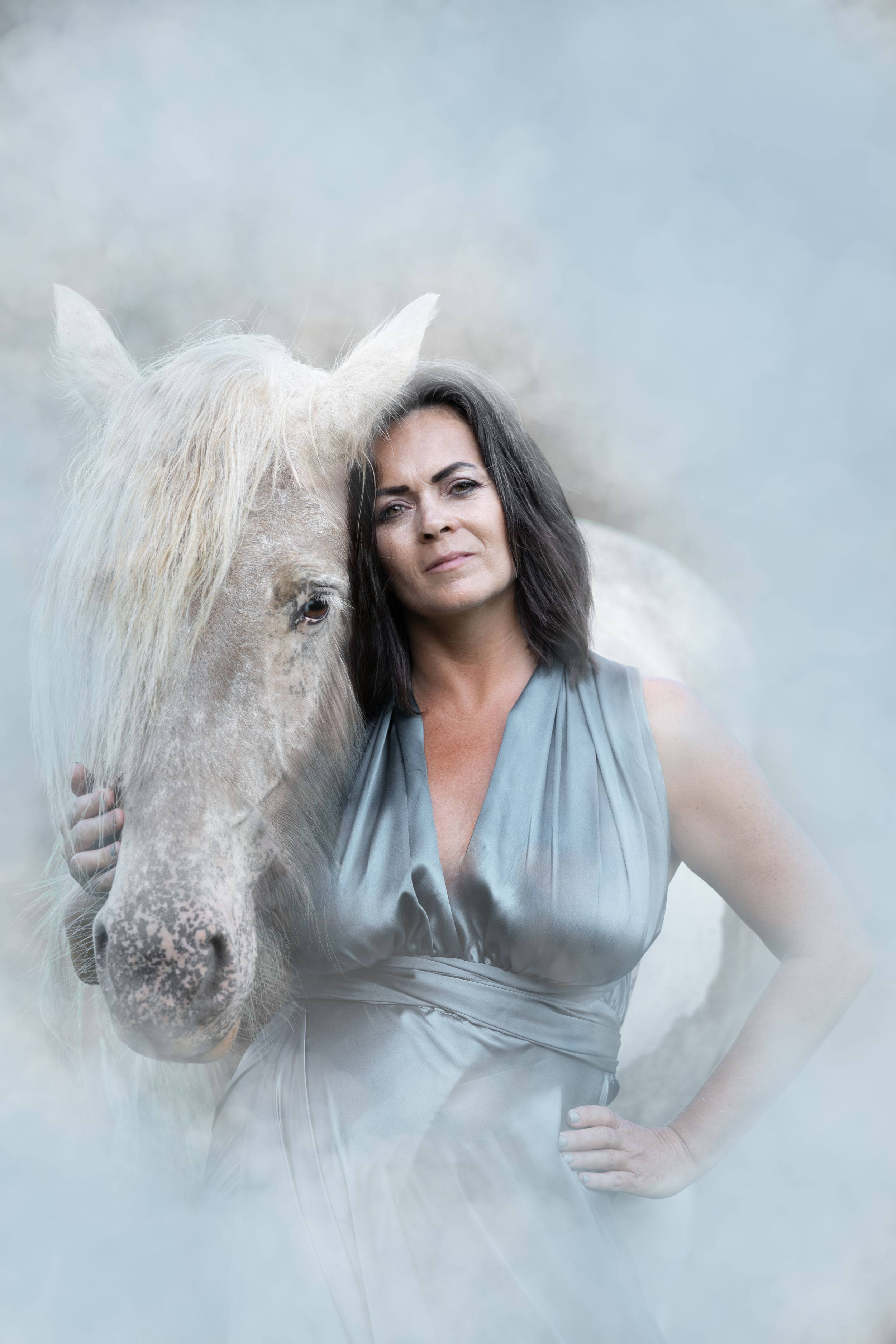 A dreamy artistic photo series featuring a horse and flowing dress against a misty light blue background.