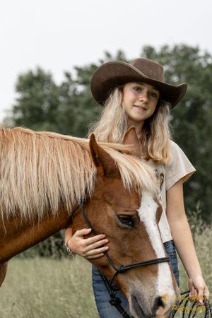 Close-up of chestnut horse with white blaze and companion in cowboy hat.