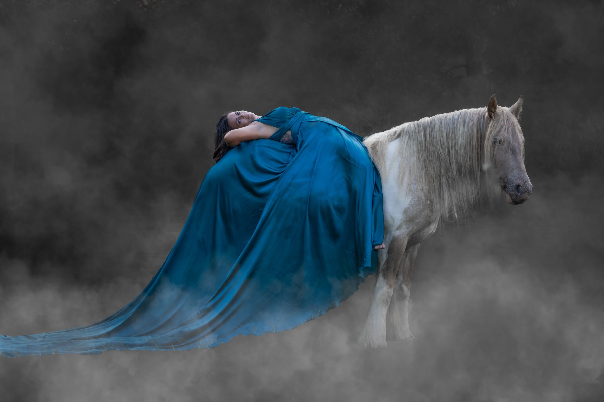 A flowing blue dress fabric creates an ethereal movement effect against a moody gray background.