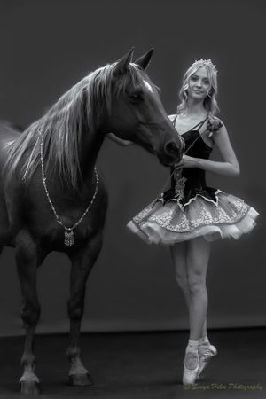 Black and white portrait capturing graceful interaction between dancer and horse.
