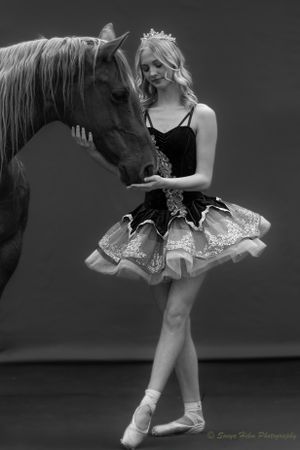 Intimate black and white portrait of ballet dancer and horse sharing quiet moment.