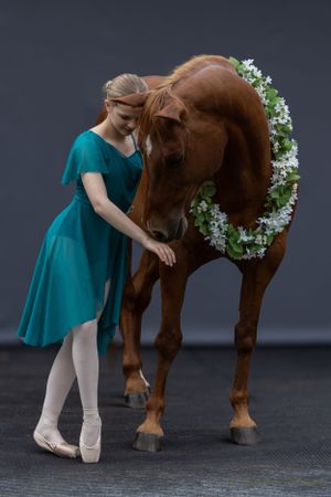 A graceful moment between dancer and horse as they share a tender interaction in a studio setting.