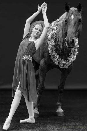 Black and white artistic dance portrait with flower-adorned horse.