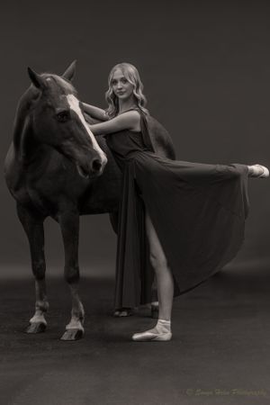 An artistic black and white dance portrait with elegant poses alongside a horse.