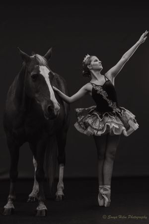 A dramatic black and white photo captures a dancer in a tutu performing alongside a horse.