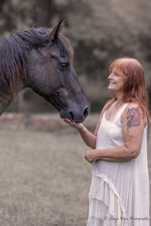 Intimate portrait of person in white dress sharing gentle moment with dark horse outdoors. Sonya Helm Equine Photography, Bristol, TN