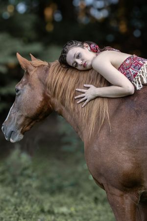 Peaceful moment with brown horse and rider resting on horseback in dappled sunlight.