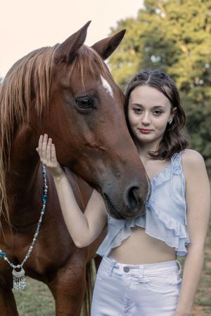 Beautiful brown horse wearing turquoise necklace in outdoor portrait with natural lighting.