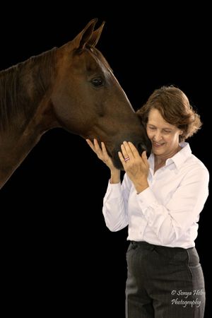 A tender interaction between a brown horse and someone in a white shirt against a dark background. Sonya Helm Equine Photography, Bristol TN