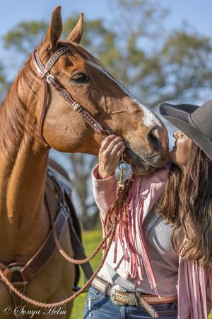 Western-styled close-up photo of horse and rider sharing an intimate moment outdoors.