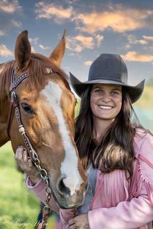 Sunset portrait of horse and rider in western attire with dramatic sky background.