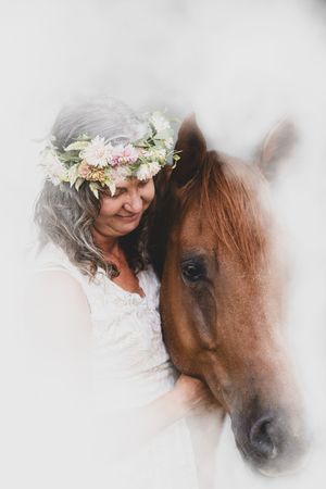Soft focus portrait of a brown horse and a figure wearing a delicate flower crown.