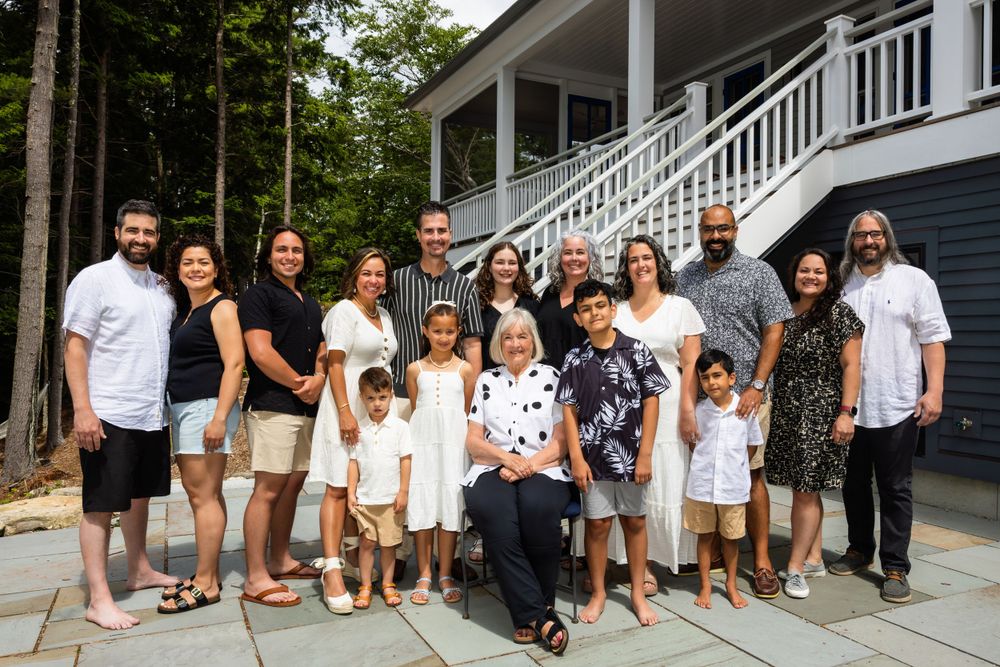 Large group photo of families in coordinated white and black outfits sitting on outdoor steps.