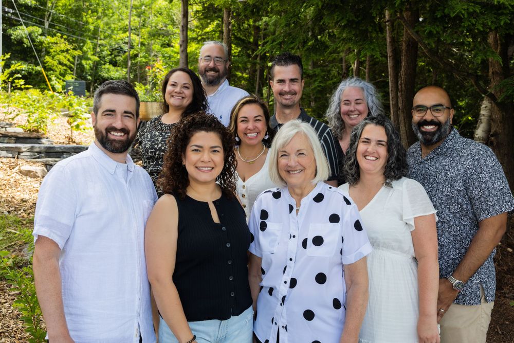 Group photo of people in casual attire standing together against a natural outdoor backdrop.